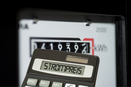 Taschenrechner mit dem Wort Strompreis im Eingabefeld, dahinter ein Stromzähler