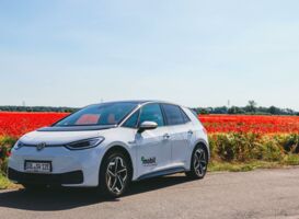 Ein E-Auto vor einem Feld voller roter Mohnblumen