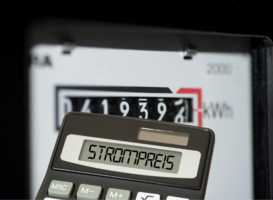 Taschenrechner mit dem Wort Strompreis im Eingabefeld, dahinter ein Stromzähler