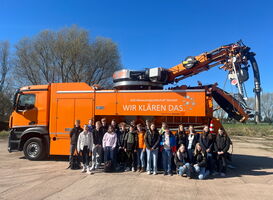 Schulklasse vor dem orangefarbenen Saugspülwagen beim Zukunftstag 2025