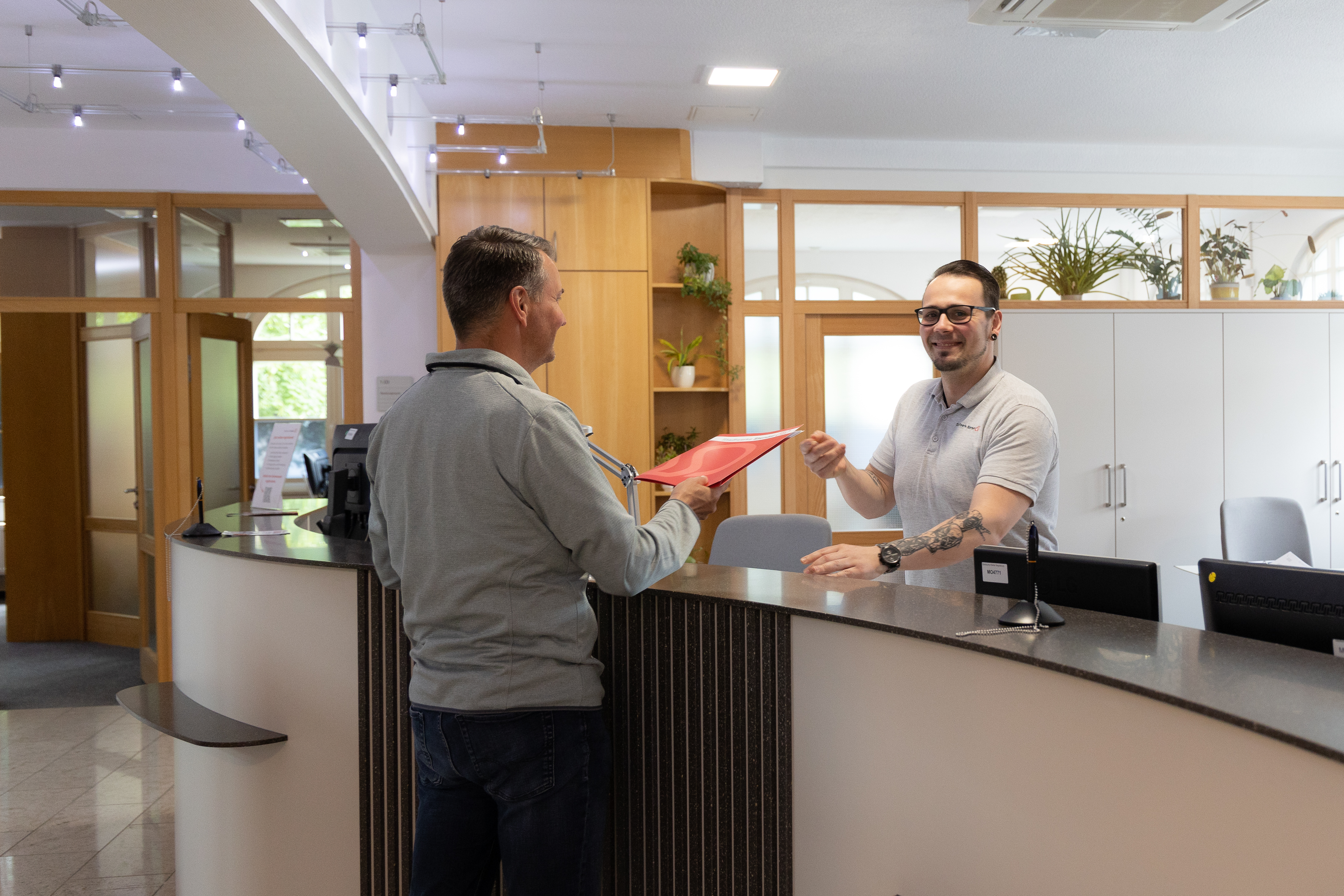 ein Kunde im Kundencenter, der am Infotresen eine Broschüre ausgehändigt bekommt